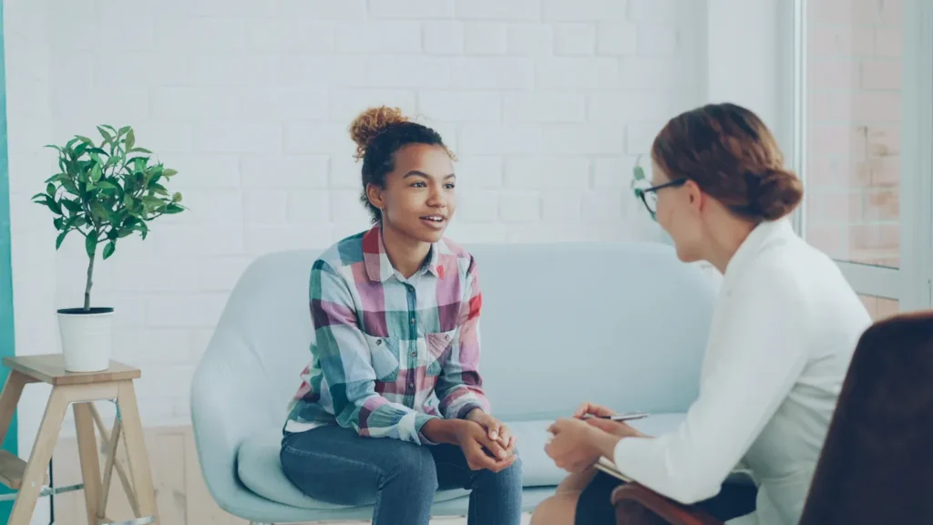 Therapist and client talking in a bright room, comparing CBT vs psychodynamic therapy